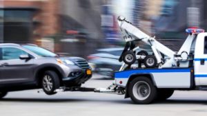 tow truck taking car to body shop with wheel lift